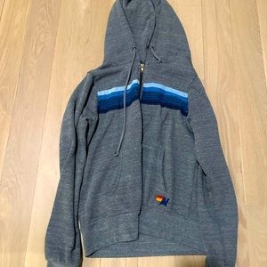 Gray aviator nation zip up with blue and white stripes across